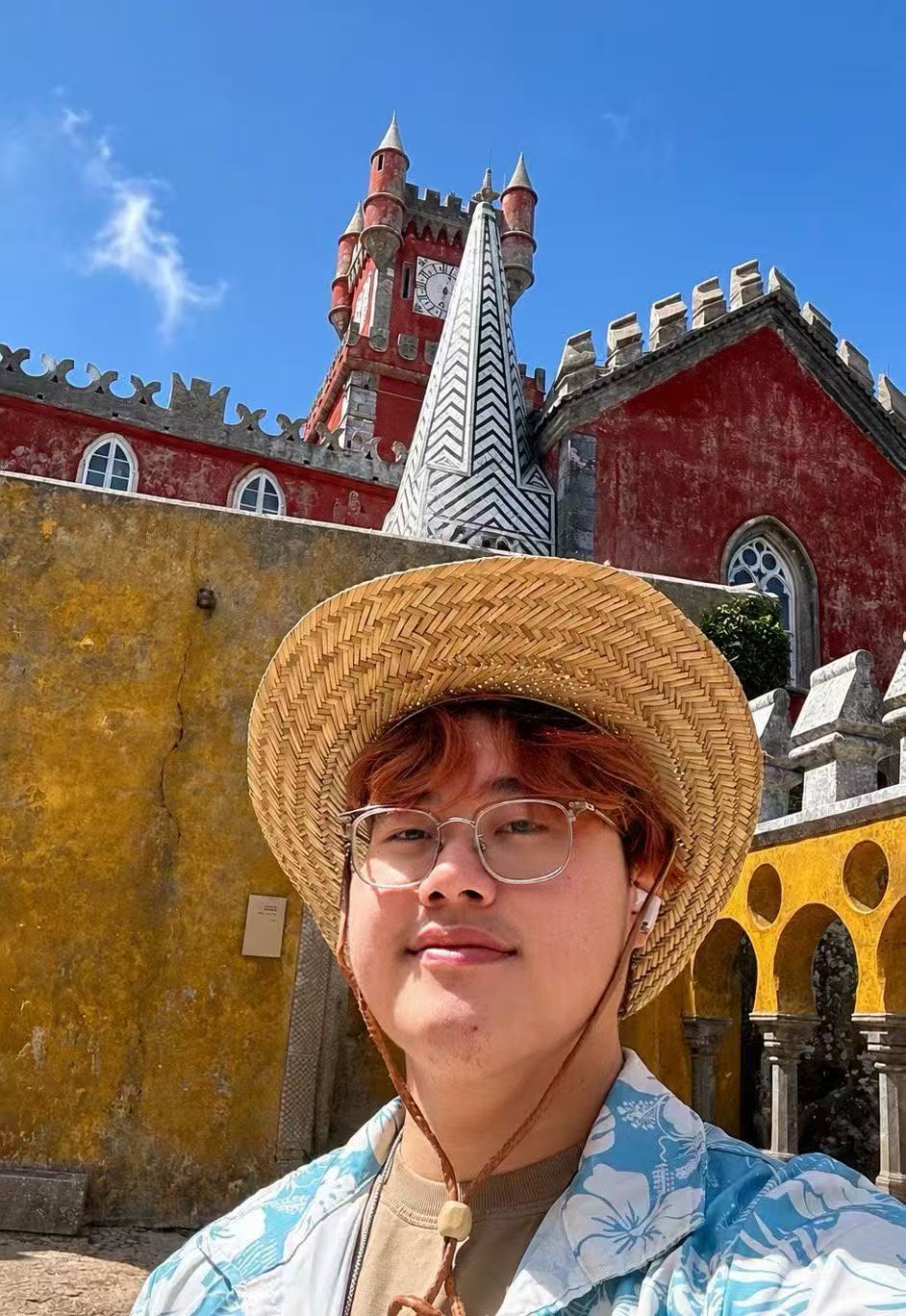 王誉翔戴着草帽,在彩色建筑前旅行留影